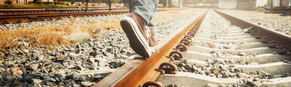 Travel and Relax copyspace background concept. Female legs in sneakers on the rail of the railway.
